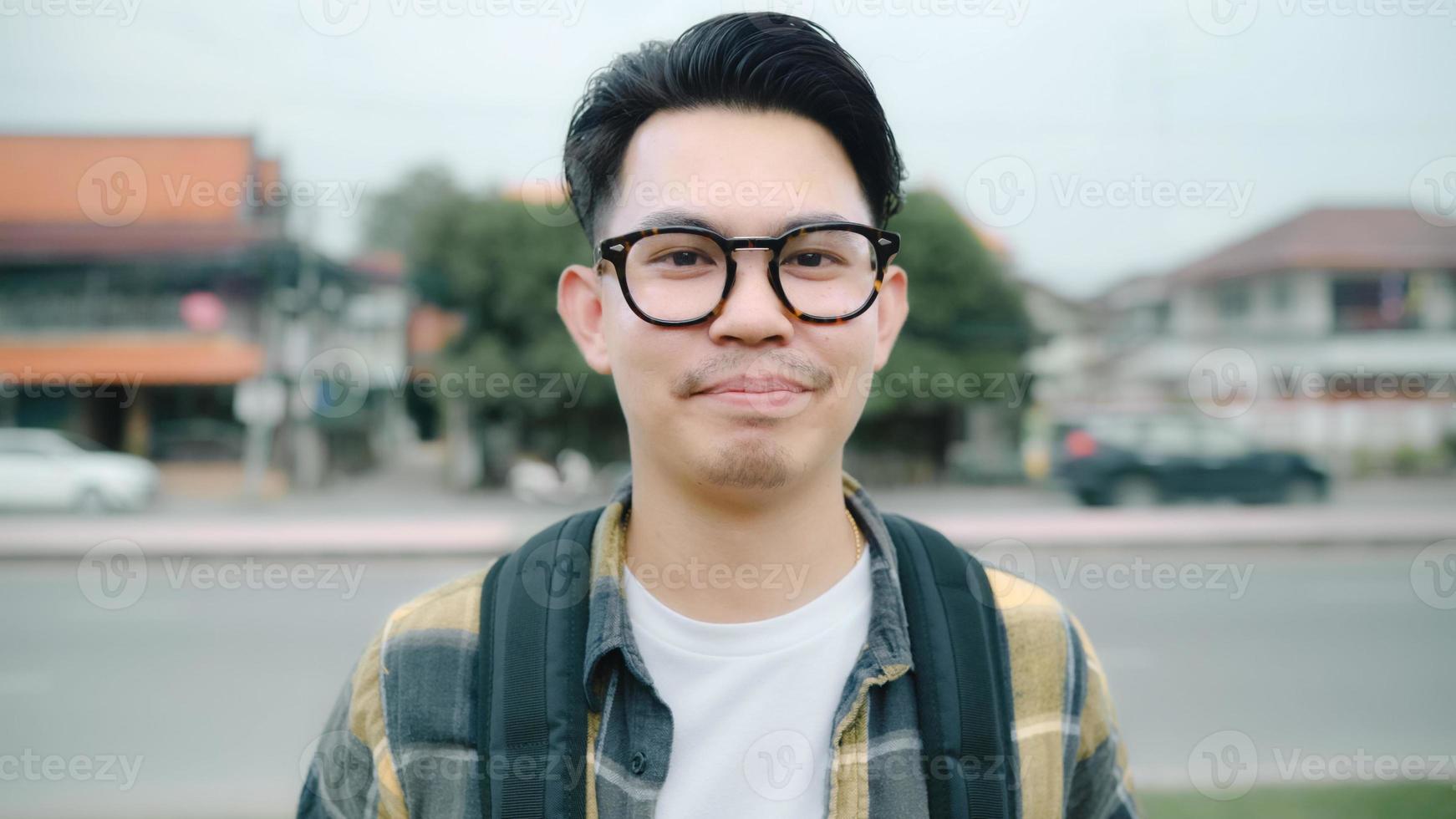 viajante homem asiático se sentindo feliz sorrindo para a viagem de férias da câmera em ayutthaya, Tailândia, mochileiro masculino desfrutar de sua jornada no incrível ponto turístico na cidade tradicional. conceito de viagens de homens de estilo de vida foto