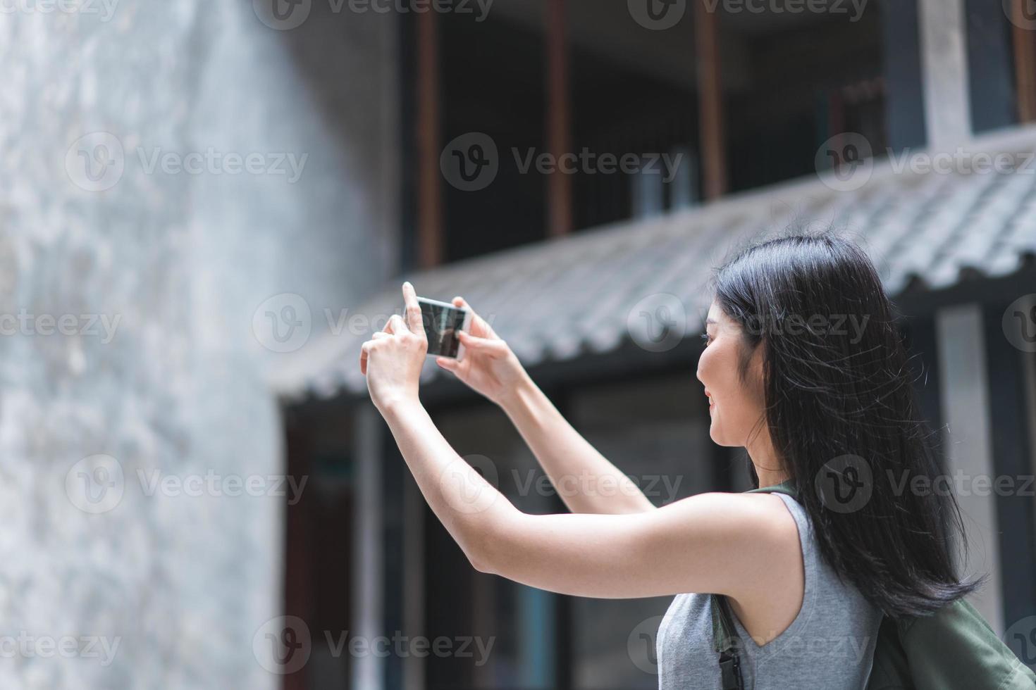 mulher asiática viajante usando telefone celular para tirar uma foto enquanto passa a viagem de férias em Pequim, China, mulher gosta de viajar em um marco incrível na cidade. mulheres de estilo de vida viajam no conceito de cidade.