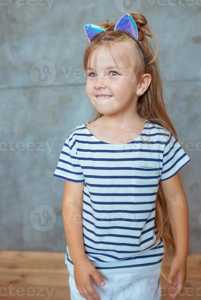 caucasiana adorável menina doce bonitinha com longos cabelos loiros em t-shirt listrada e orelhas de gato foto