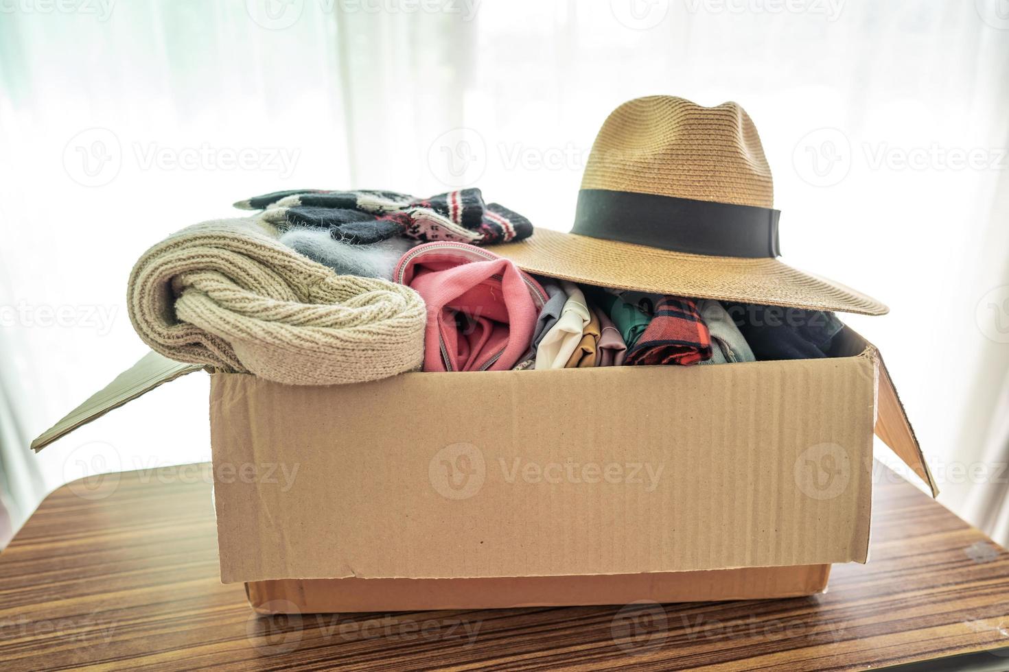 segurando a caixa de doação de roupas com roupas usadas e chapéu em casa para ajudar as pessoas pobres do mundo. foto