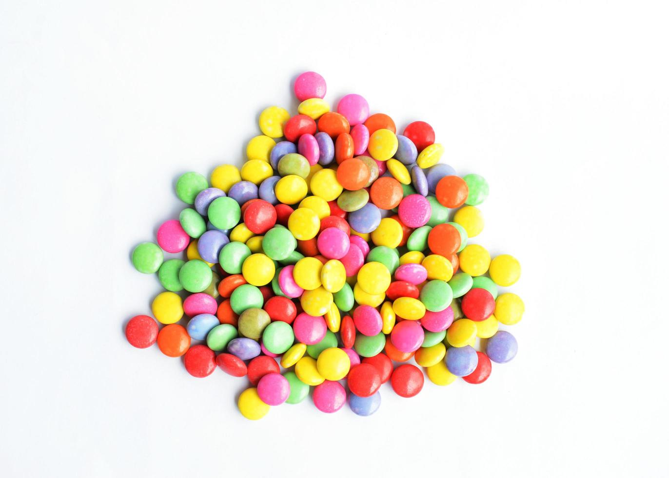 uma pilha de doces revestidos de chocolate coloridos isolados em fundos brancos acima foto