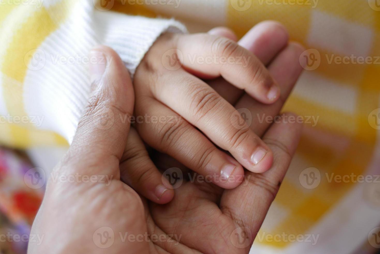 pai segurando a mão do filho bebê, close-up. foto