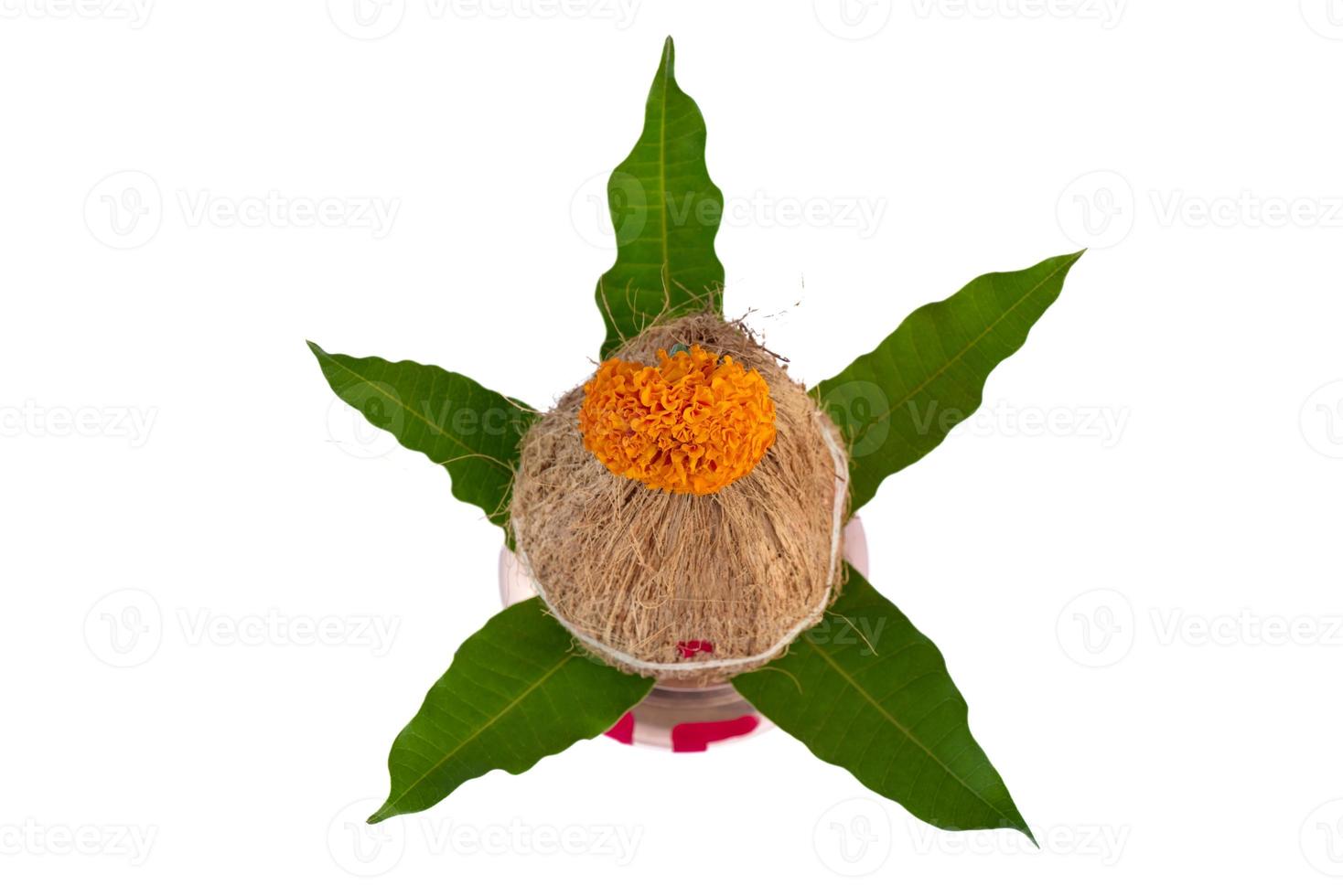 kalash de cobre com coco e folha de manga com decoração floral em fundo branco. essencial no puja hindu. foto
