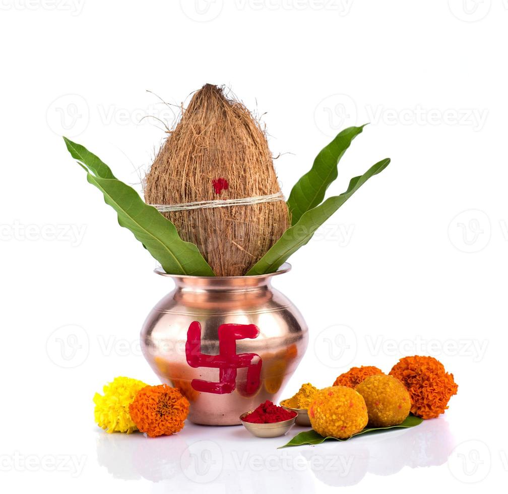 kalash de cobre com coco, folha de manga, haldi, kumkum e doces com decoração de flor de calêndula em um fundo branco. essencial no puja hindu. foto