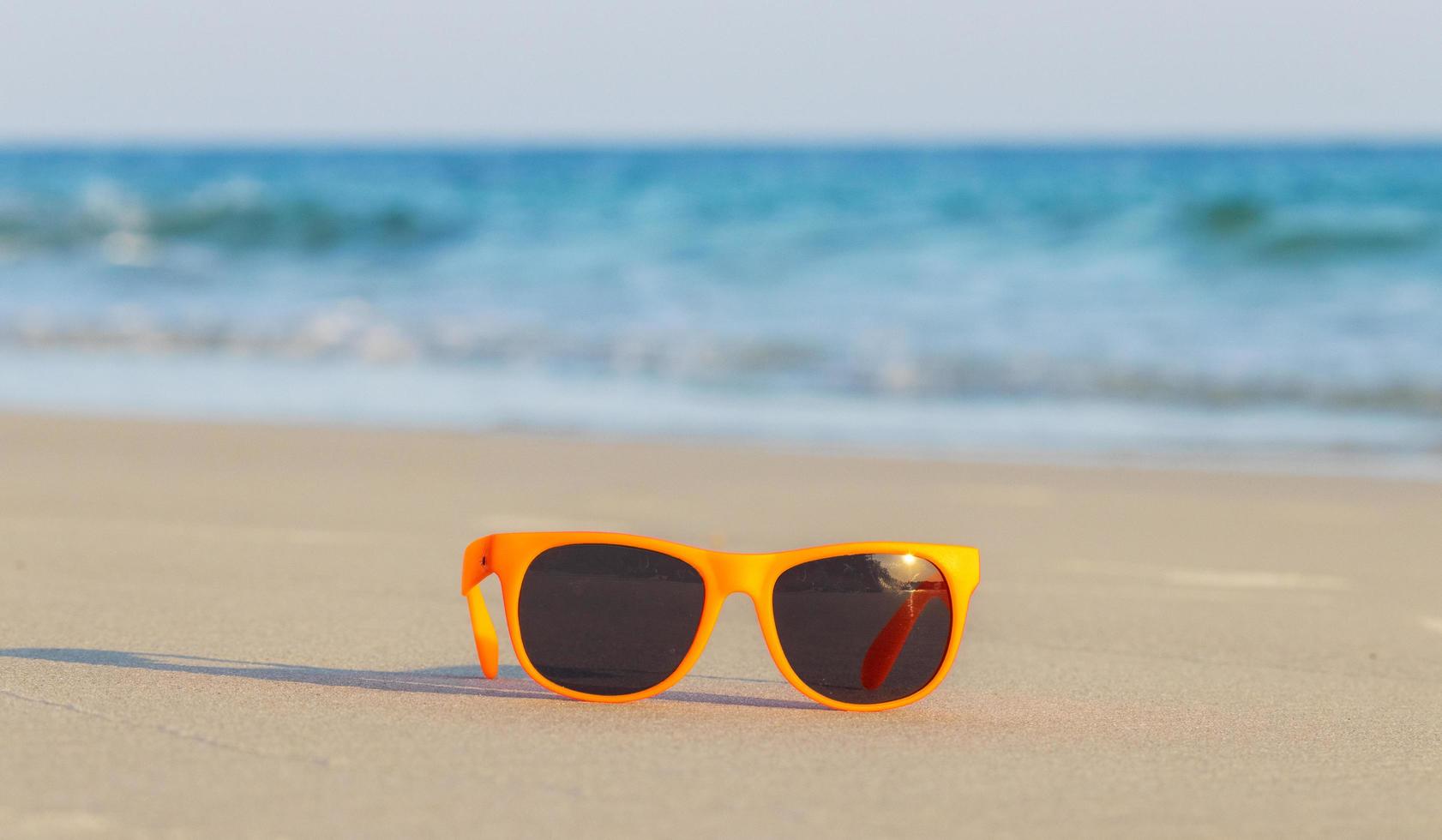 óculos de sol de moda na areia linda praia de verão foto