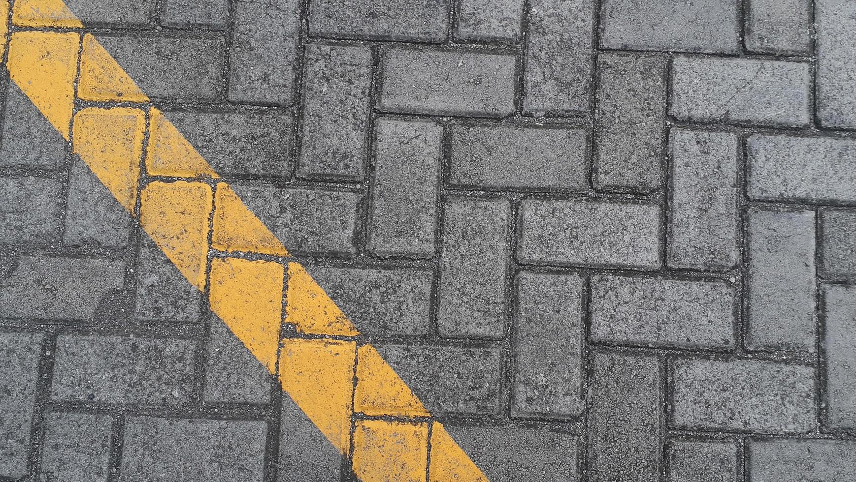 laje de pavimentação rua urbana cinza com linhas amarelas diagonais marcações de estrada fundo de textura de telha de pedra foto