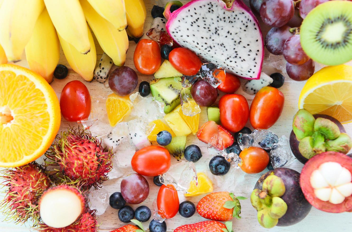 fundo de salada de frutas fresco verão frutas e legumes saudável comida orgânica morangos laranja kiwi mirtilos fruta do dragão banana tropical mangostão rambutan uva abacaxi tomate limão foto