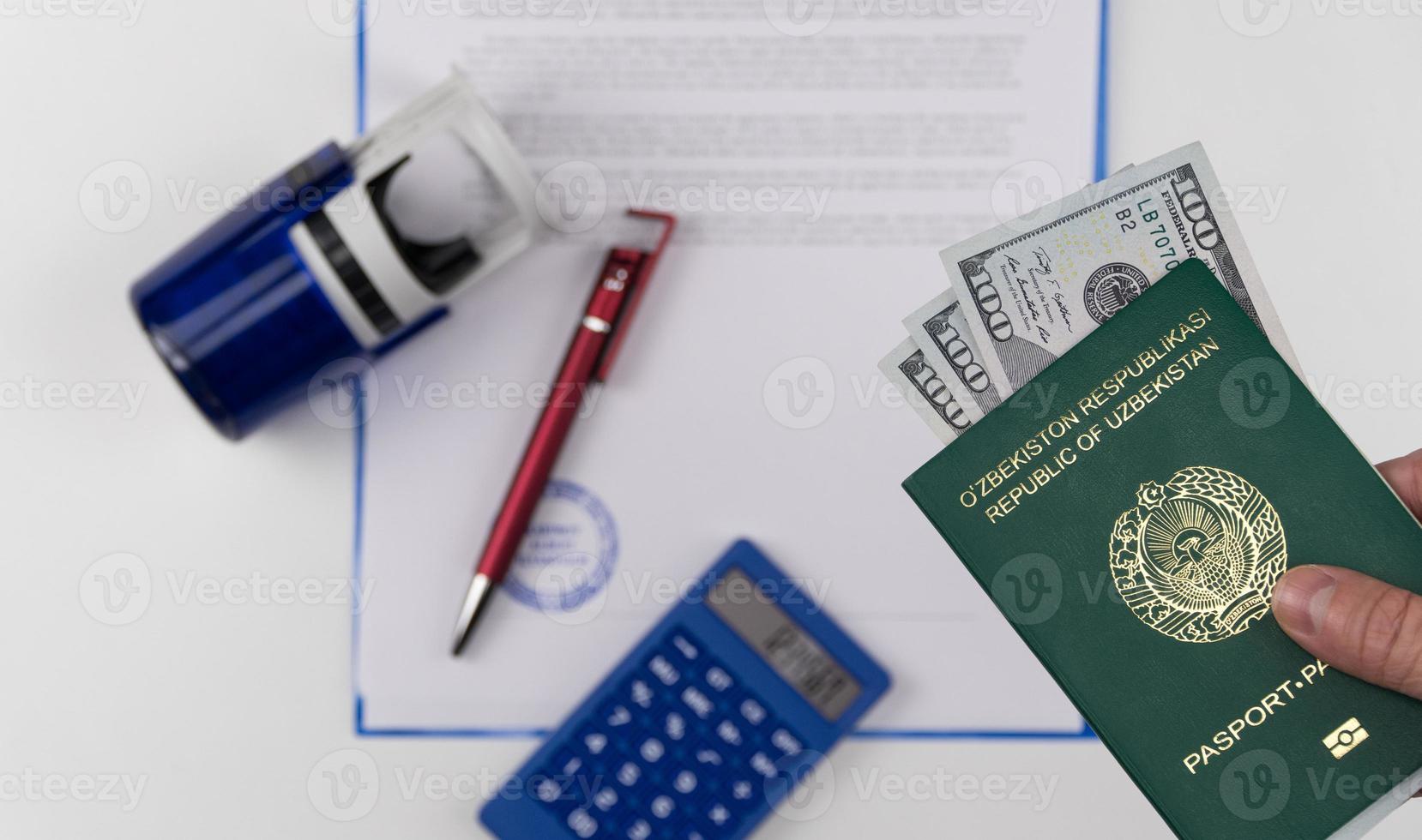 mão segura o passaporte do uzbequistão com dólares americanos no fundo de documentos e carimbo de borracha. conceito - suborno e corrupção foto