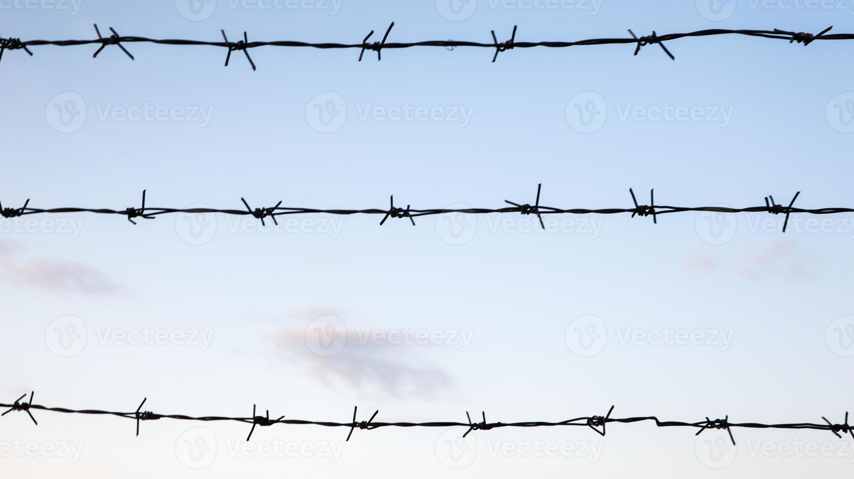 arame farpado contra um céu azul closeup. cerca ou cerca em uma área fechada. foto