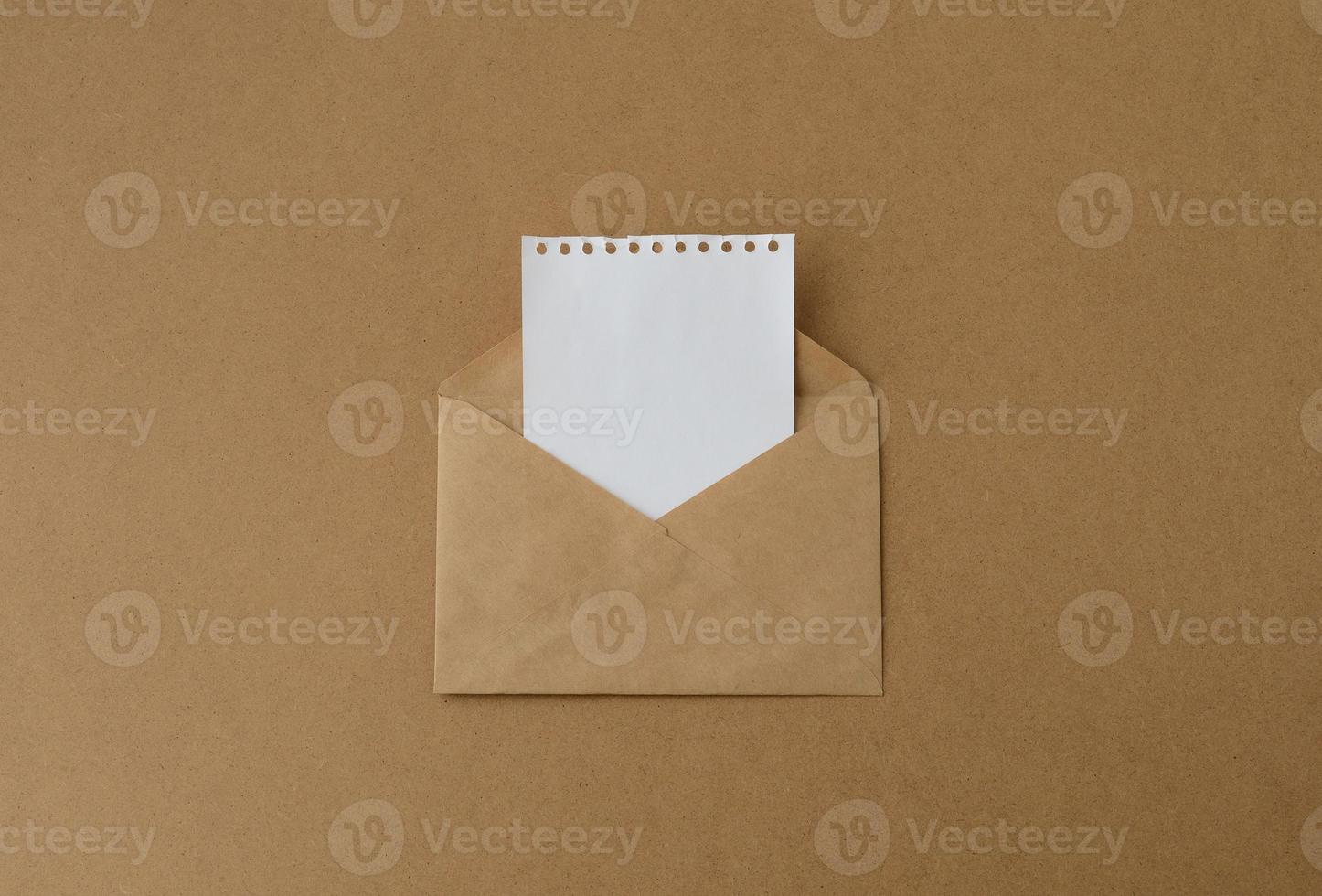 envelope marrom com um cartão branco em branco, um envelope de papel kraft com uma folha branca de um notebook foto