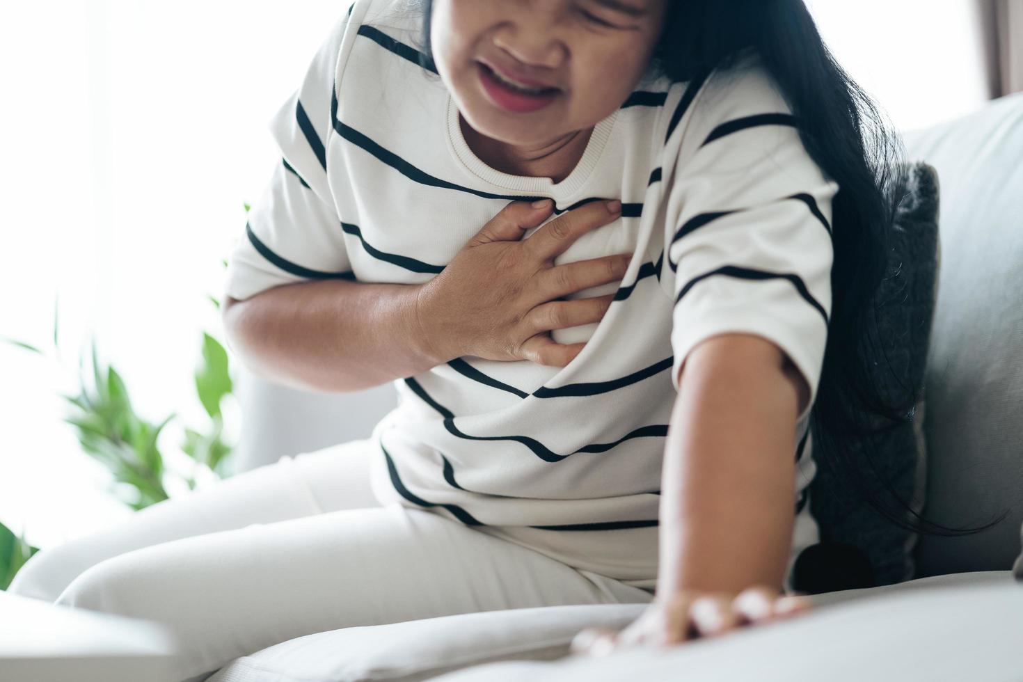 closeup de mulher asiática tendo ataque cardíaco. mulher tocando o peito e com dor no peito. cuidados de saúde e conceito médico. foto