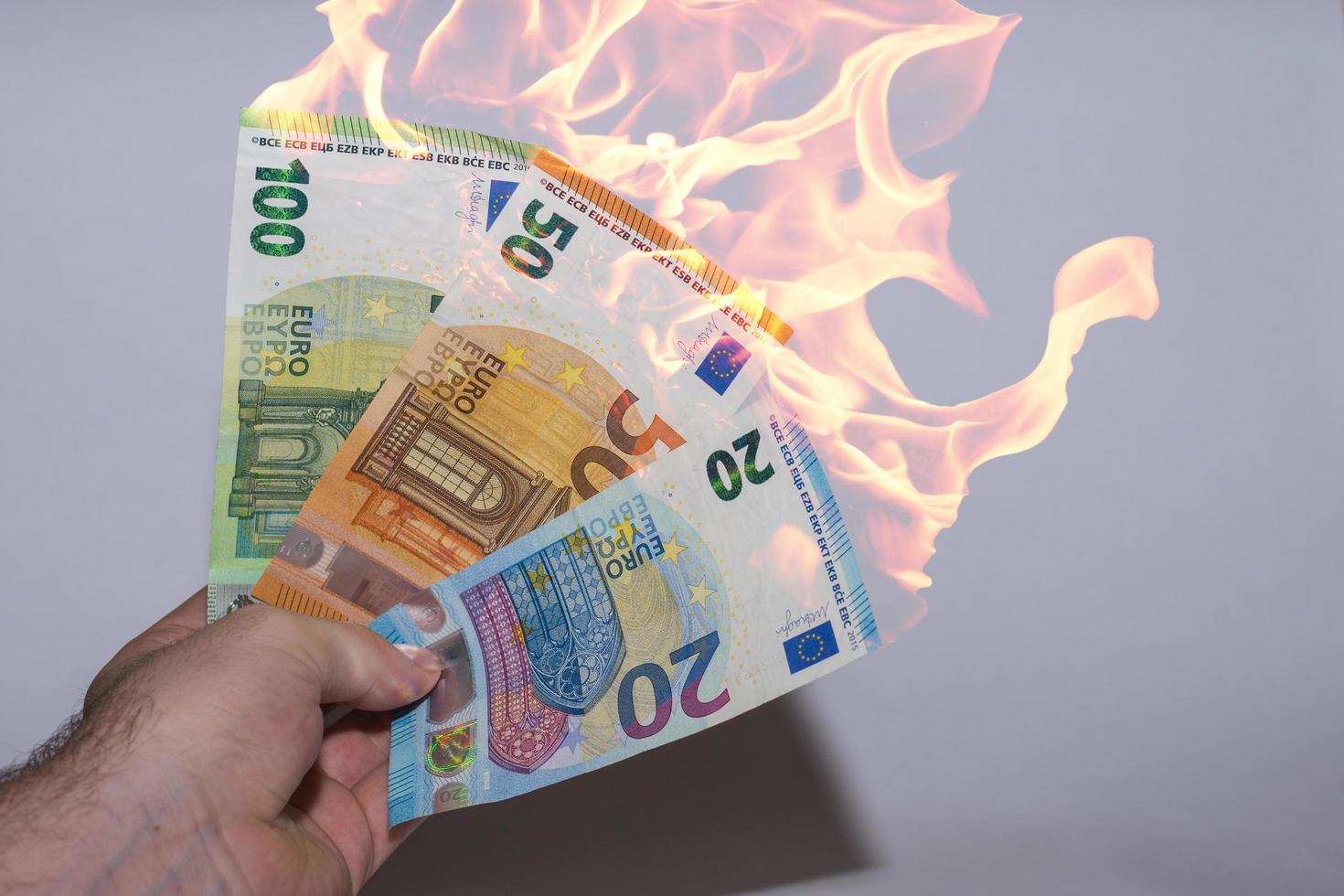 mão segurando três notas de euro em chamas inflação nas finanças foto