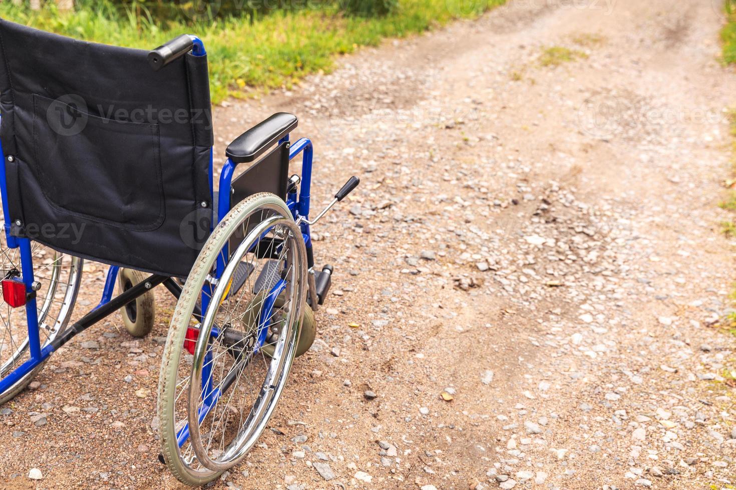 cadeira de rodas vazia em pé na estrada à espera de serviços ao paciente. cadeira de rodas para pessoas com deficiência estacionada ao ar livre. acessível para pessoa com deficiência. conceito médico de cuidados de saúde. foto