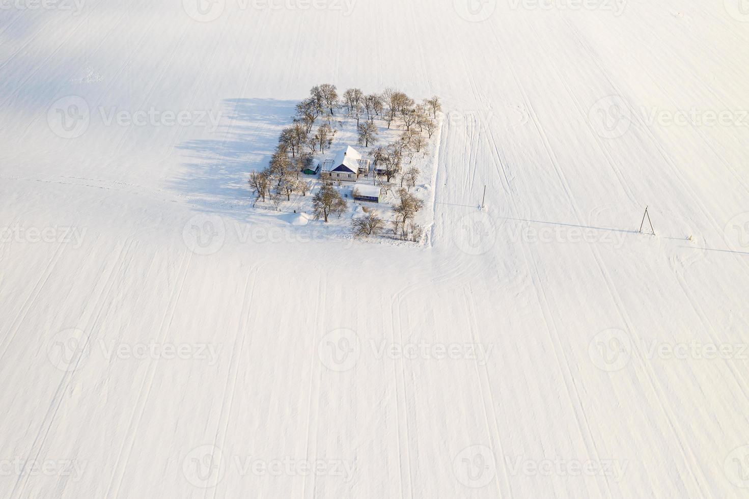casa solitária no meio de uma vista superior do campo coberto de neve. foto