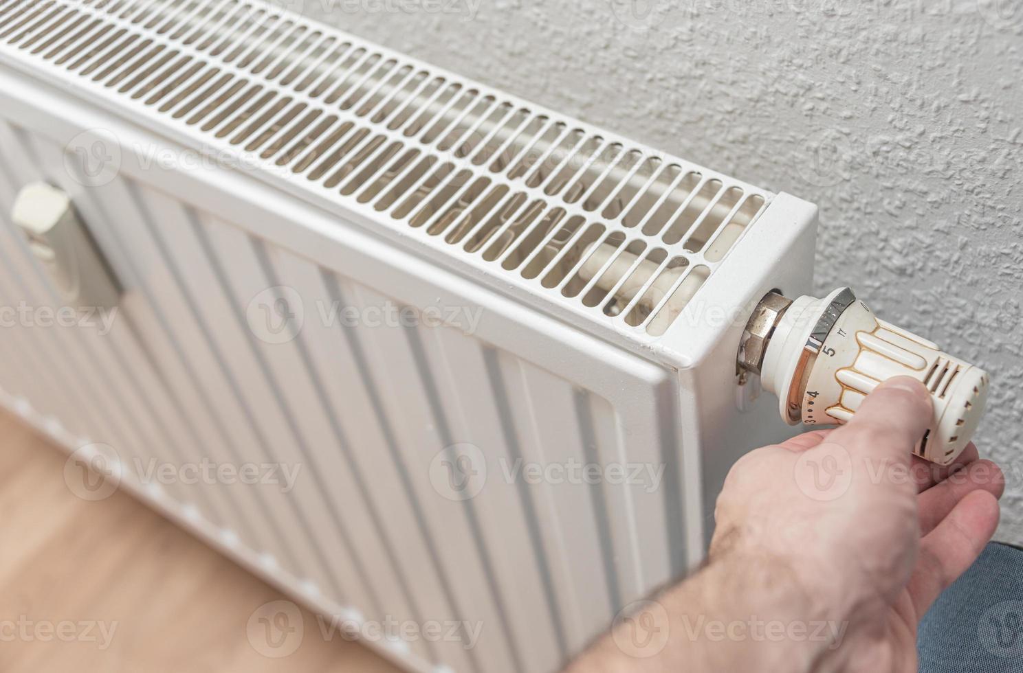 bateria de aquecimento da casa com configuração de potência máxima de aquecimento e a mão do homem está ajustando seu mostrador. conceito de consumo de energia em residências. foto