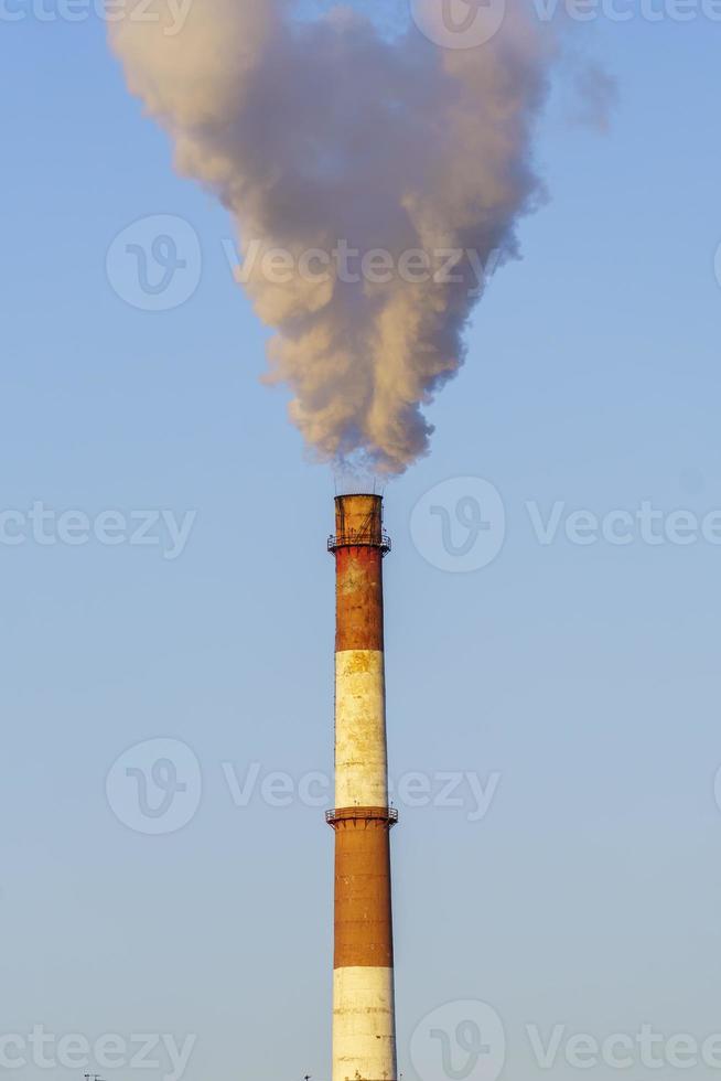 fumaça branca e espessa da chaminé da sala das caldeiras. fumaça contra o céu azul. foto