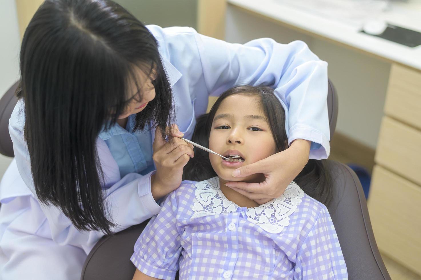 uma menina bonita tendo os dentes examinados pelo dentista na clínica odontológica, check-up de dentes e conceito de dentes saudáveis foto