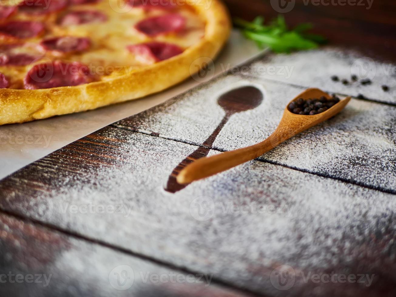 pimenta preta em uma colher de pau na mesa da cozinha foto