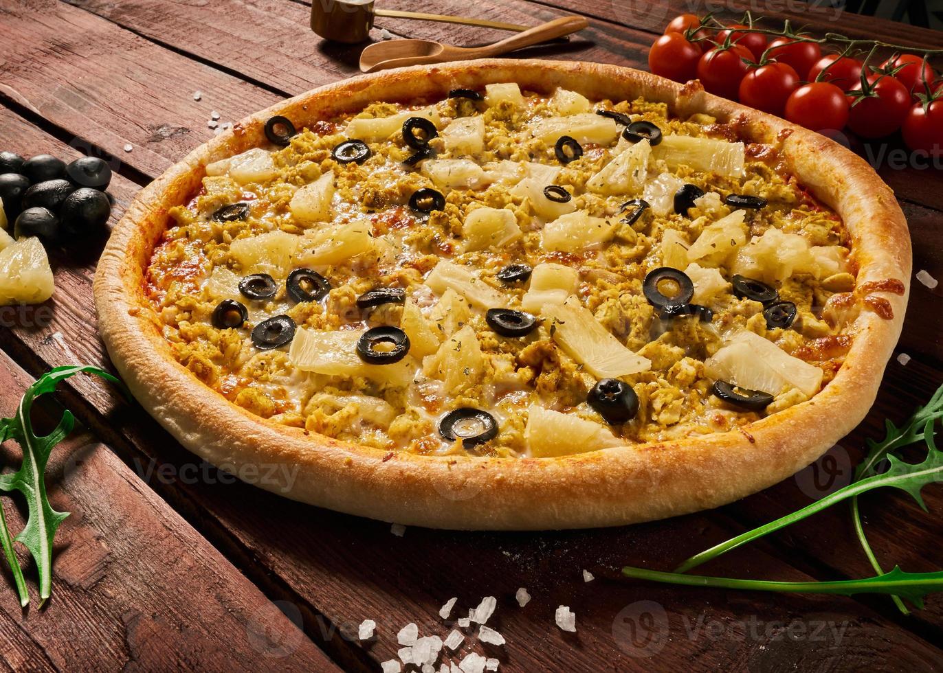pizza com frango e abacaxi em uma mesa de madeira foto
