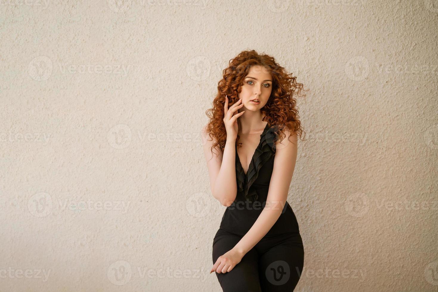 uma jovem ruiva posa contra uma parede, um lugar para uma inscrição. menina elegante e elegante foto