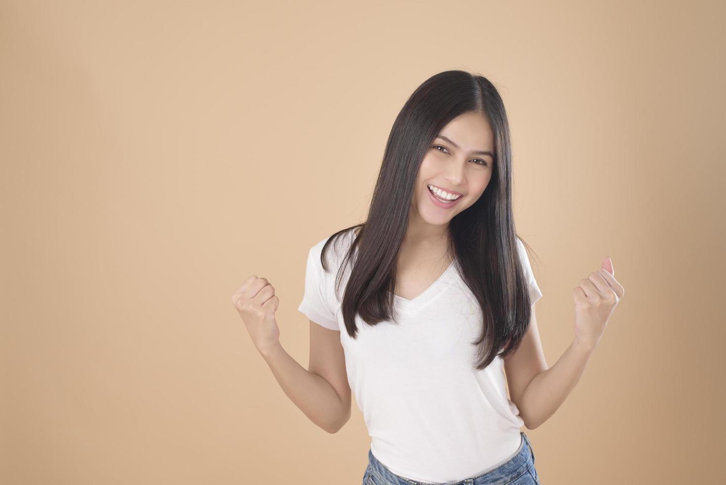 um retrato de mulher asiática com camiseta branca sobre estúdio de fundo marrom claro foto