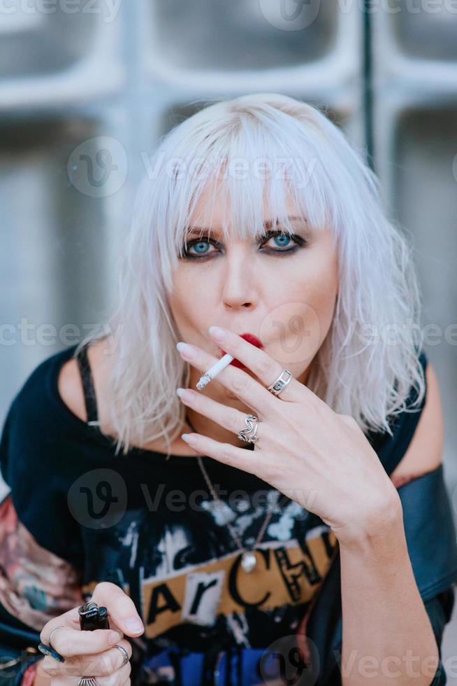 retrato de uma jovem loira elegante grunge com maquiagem fumando cigarro foto