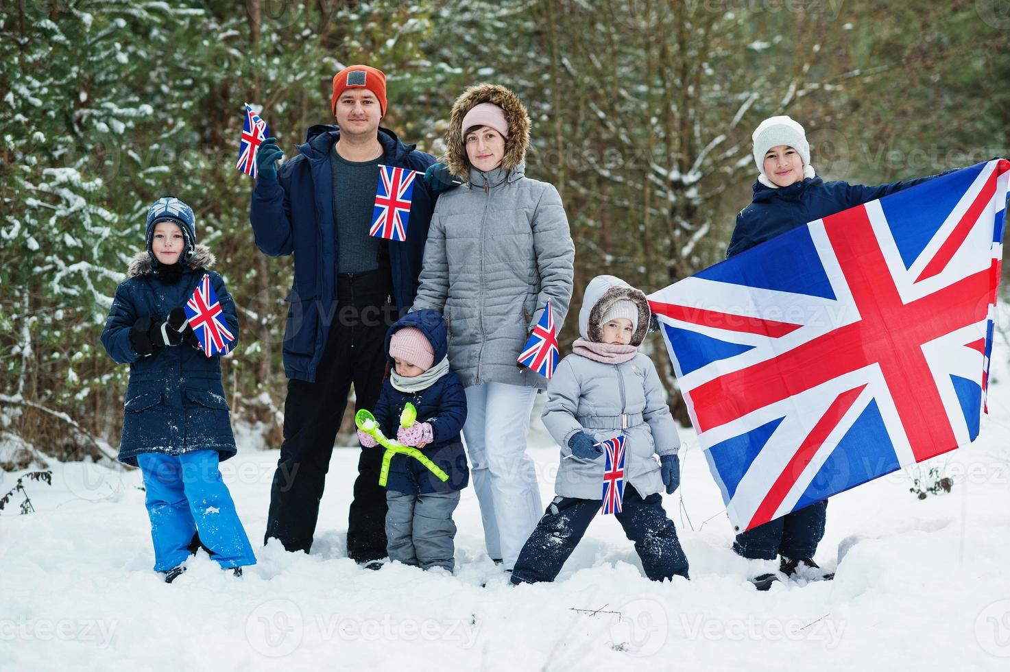 família com quatro filhos segurando a bandeira da grã-bretanha na paisagem de inverno. foto