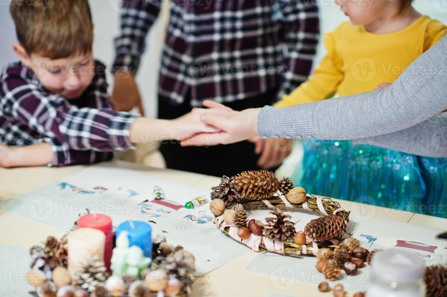 mãos de mãe e filhos fazem uma guirlanda para a véspera de natal e decoração de artesanato. celebração de Ano Novo. foto