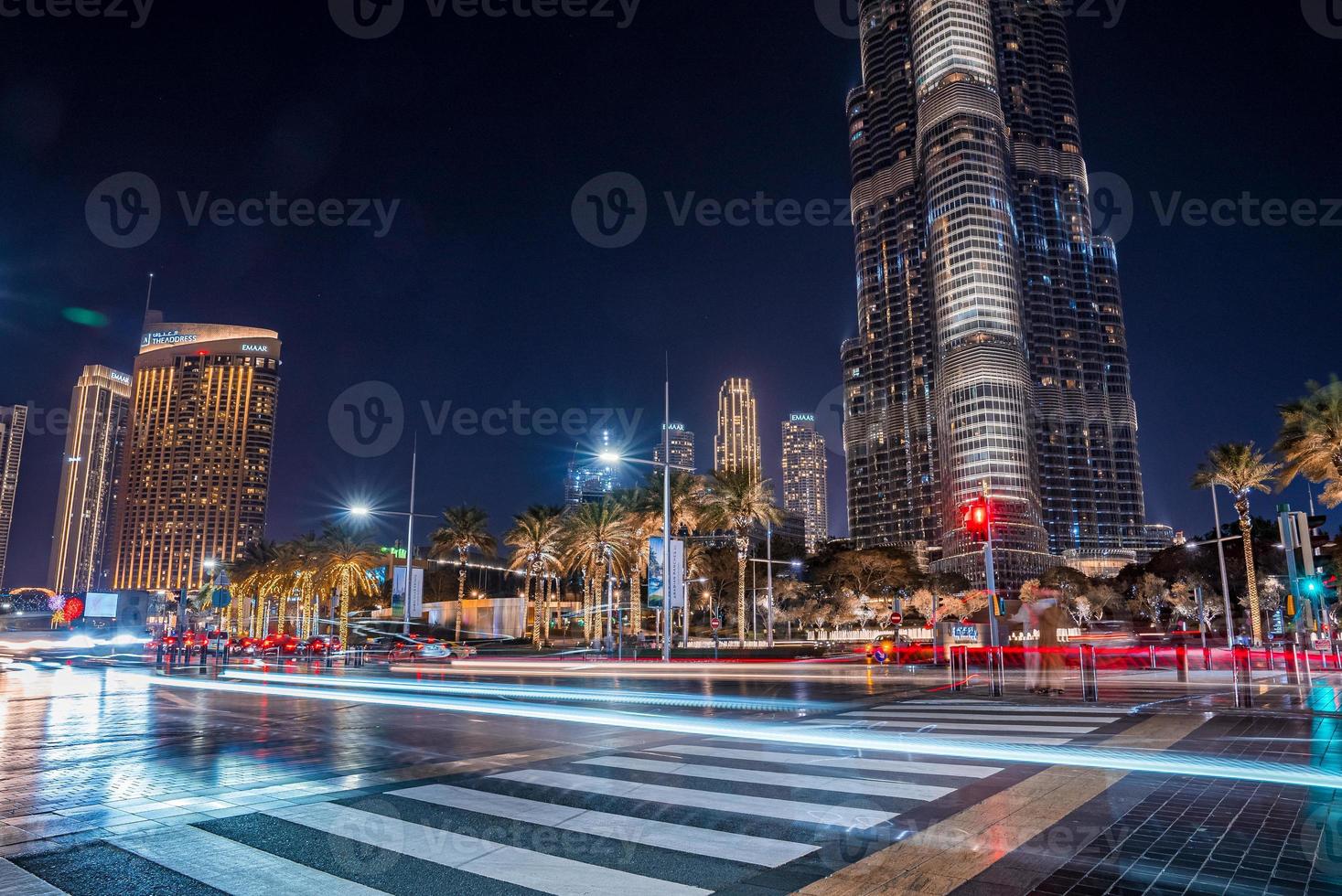 arranha-céu burj khalifa à noite em dubai. encruzilhada movimentada com carros e pedestres no meio de dubai. foto