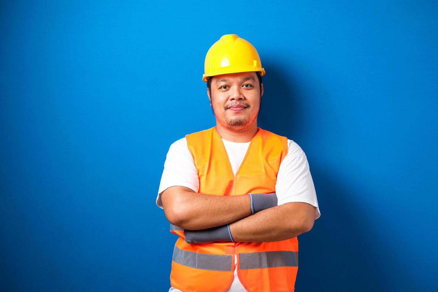 cara asiático usando capacete e colete de segurança sorri para a câmera foto