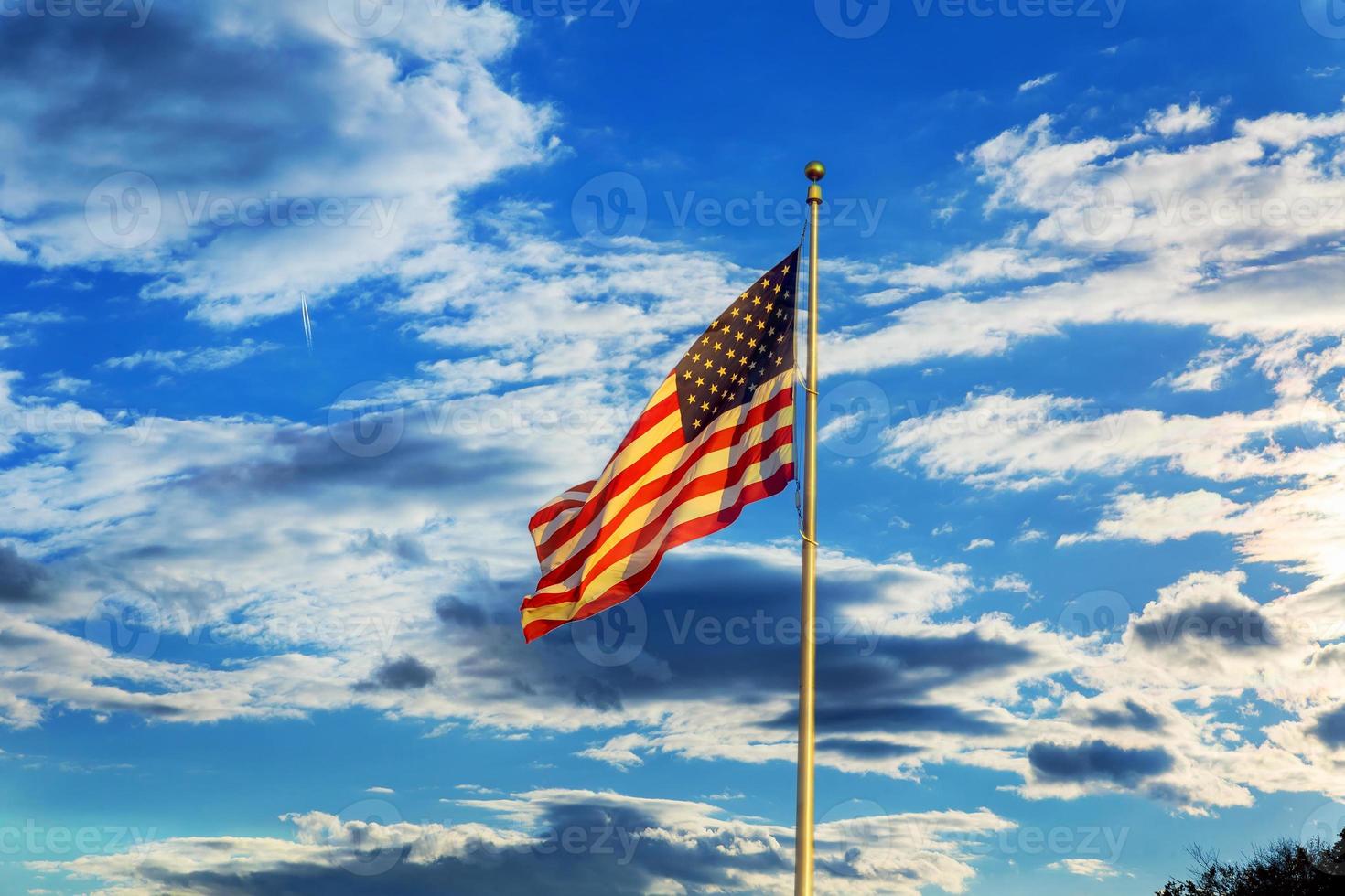 bandeira americana voando na brisa contra o céu azul com nuvens brancas foto