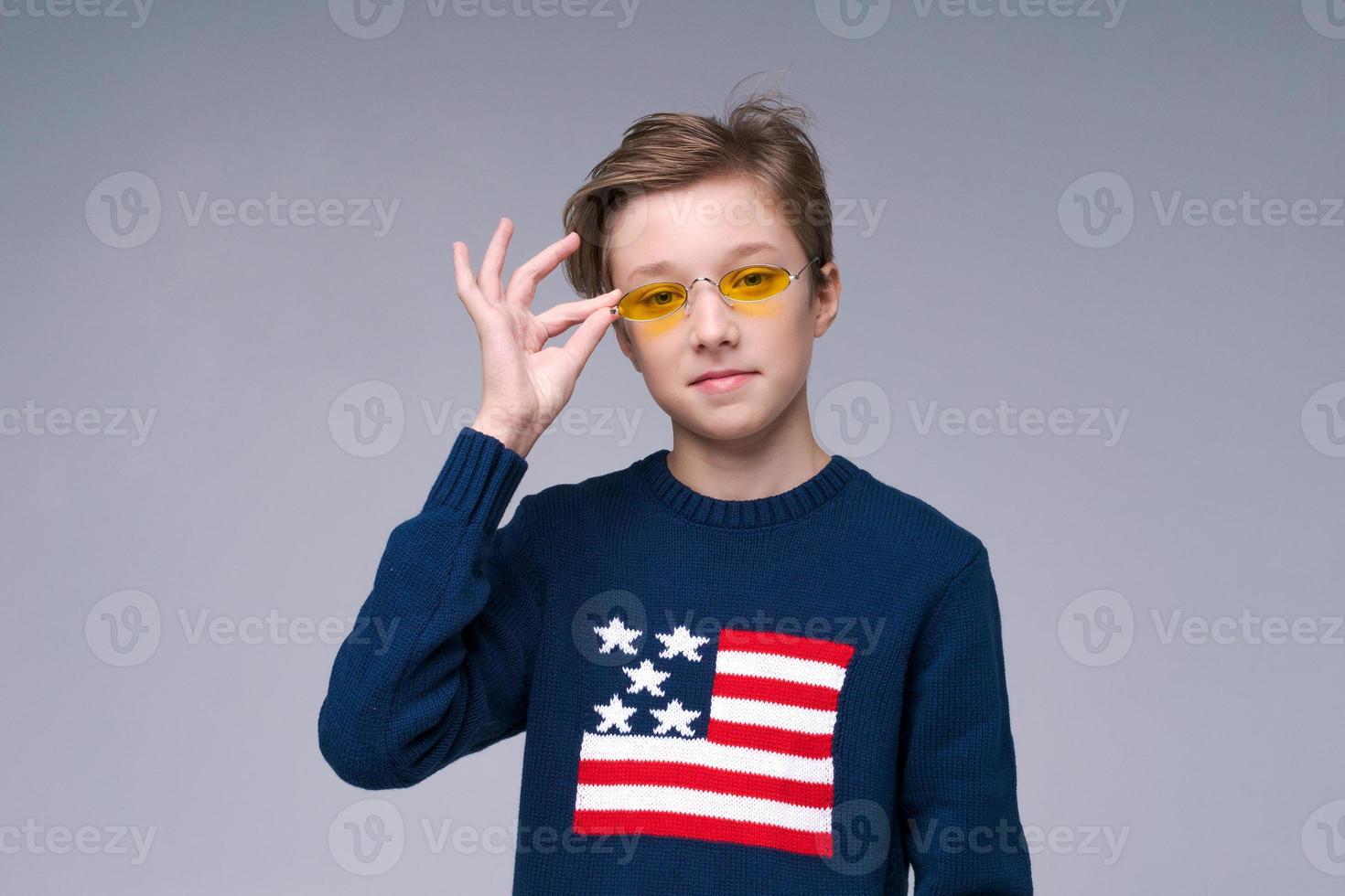 feliz homem europeu usando óculos amarelos e suéter azul da bandeira dos eua em cinza foto