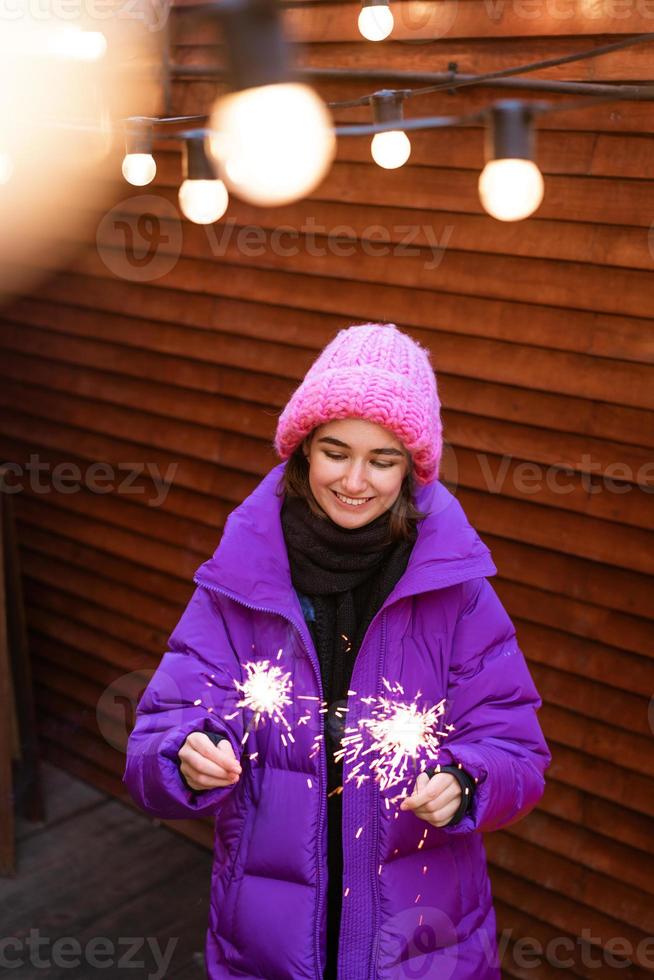 garota caucasiana está se divertindo no inverno na rua com estrelinhas na mão foto