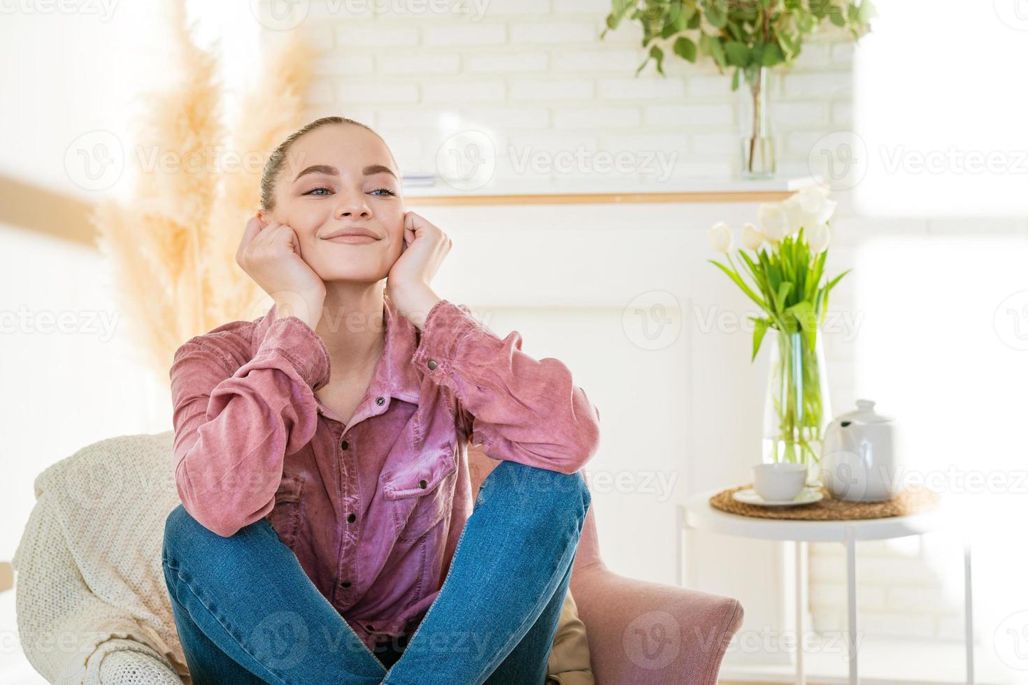 sorridente garota milenar caucasiana sentada descansando na cadeira em roupas casuais foto