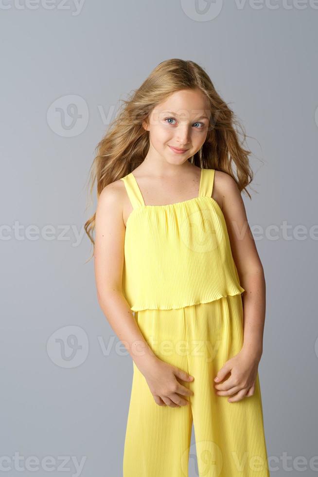 linda garota com cabelo comprido em poses amarelas sobre um fundo branco. foto