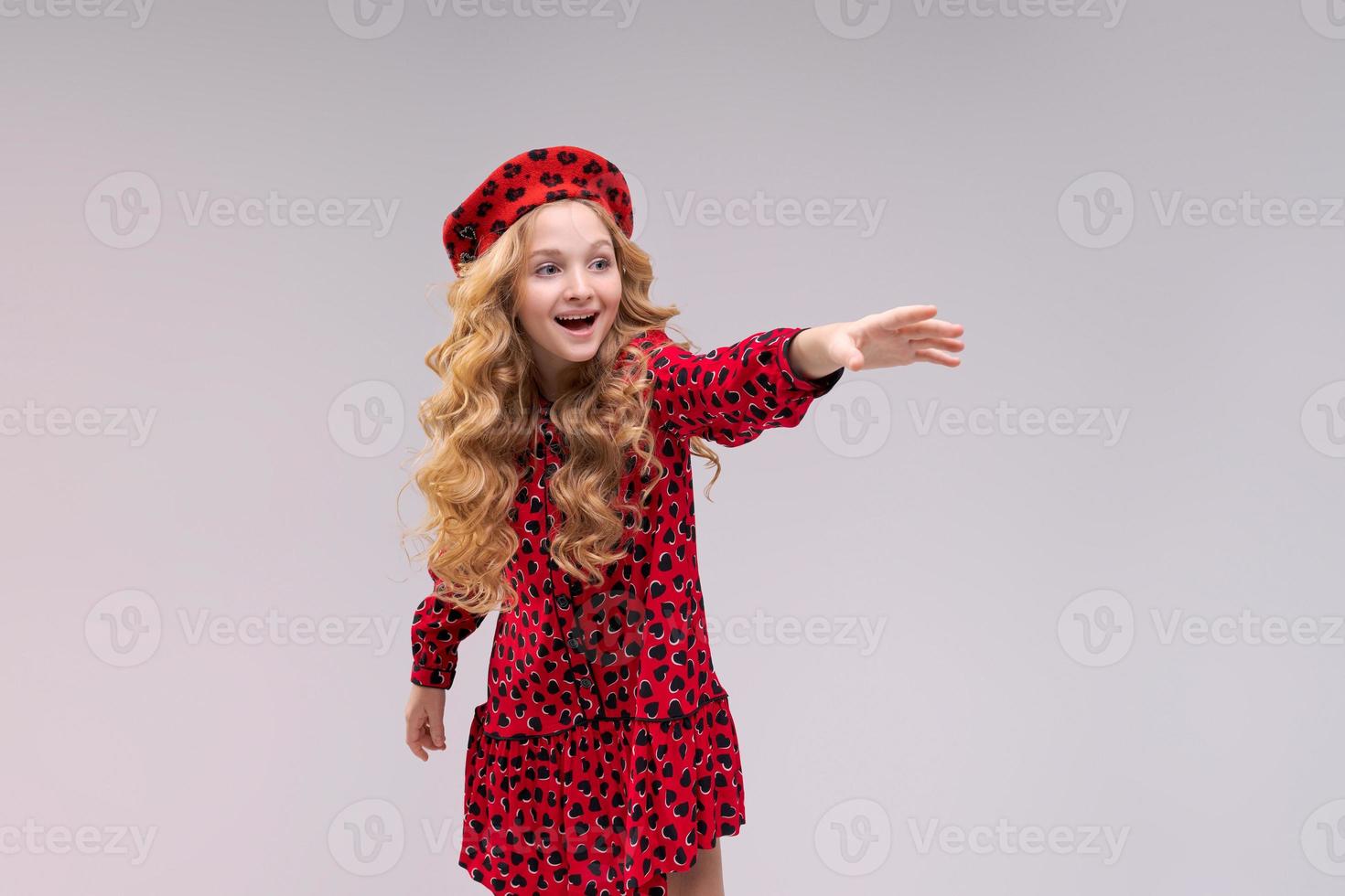 menina com chapéu de estilo francês aponta o dedo para o lado. menina feliz com longa foto