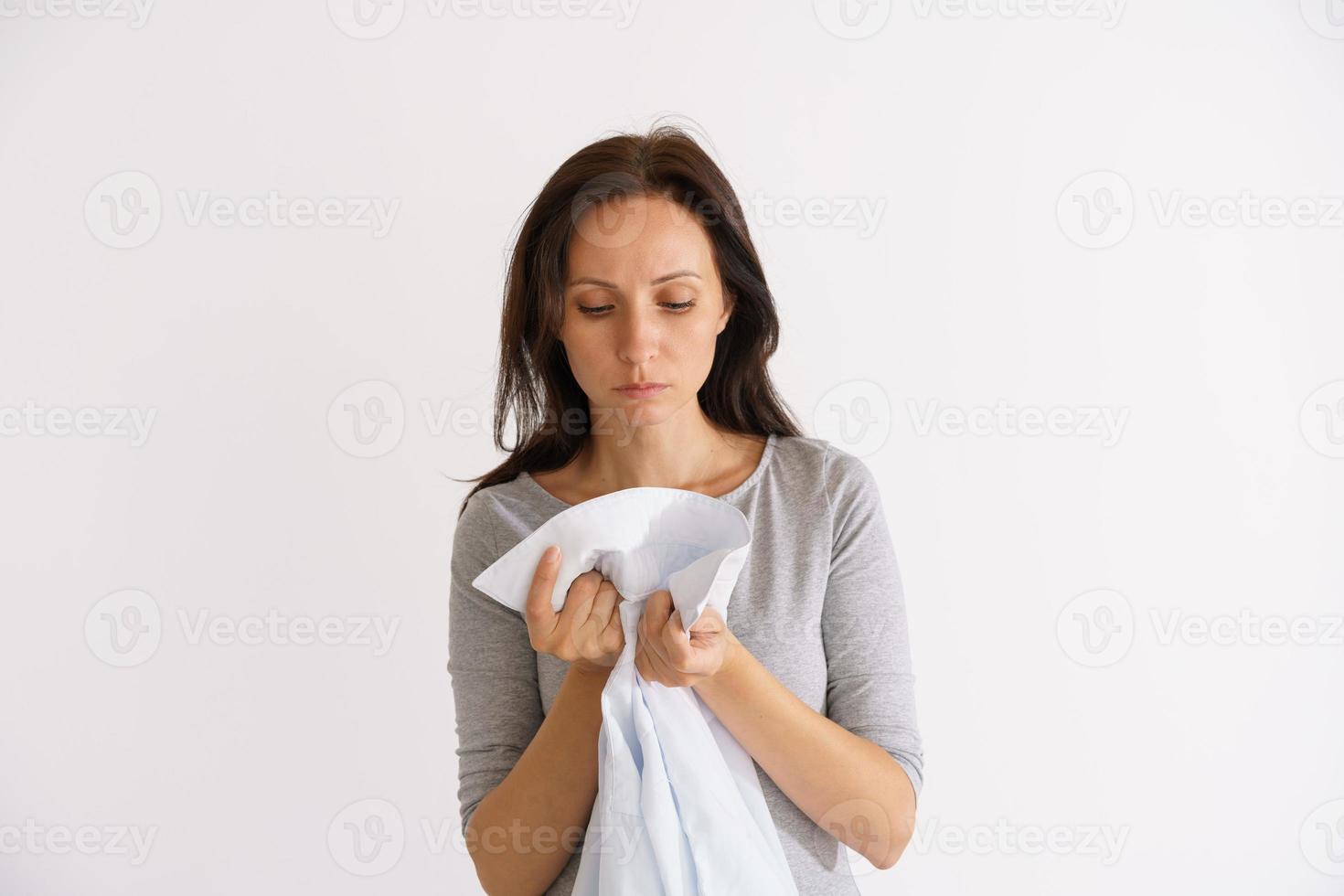 mulher cheirando camisa limpa em fundo claro foto