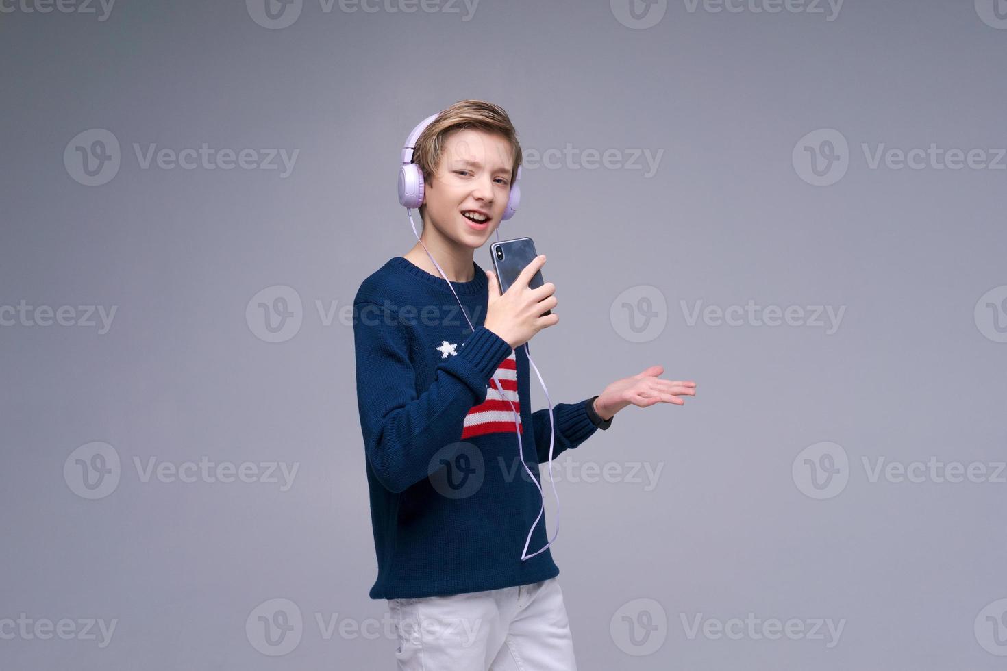 jovem alegre vestindo suéter azul conosco bandeira fones de ouvido cantando uma música foto