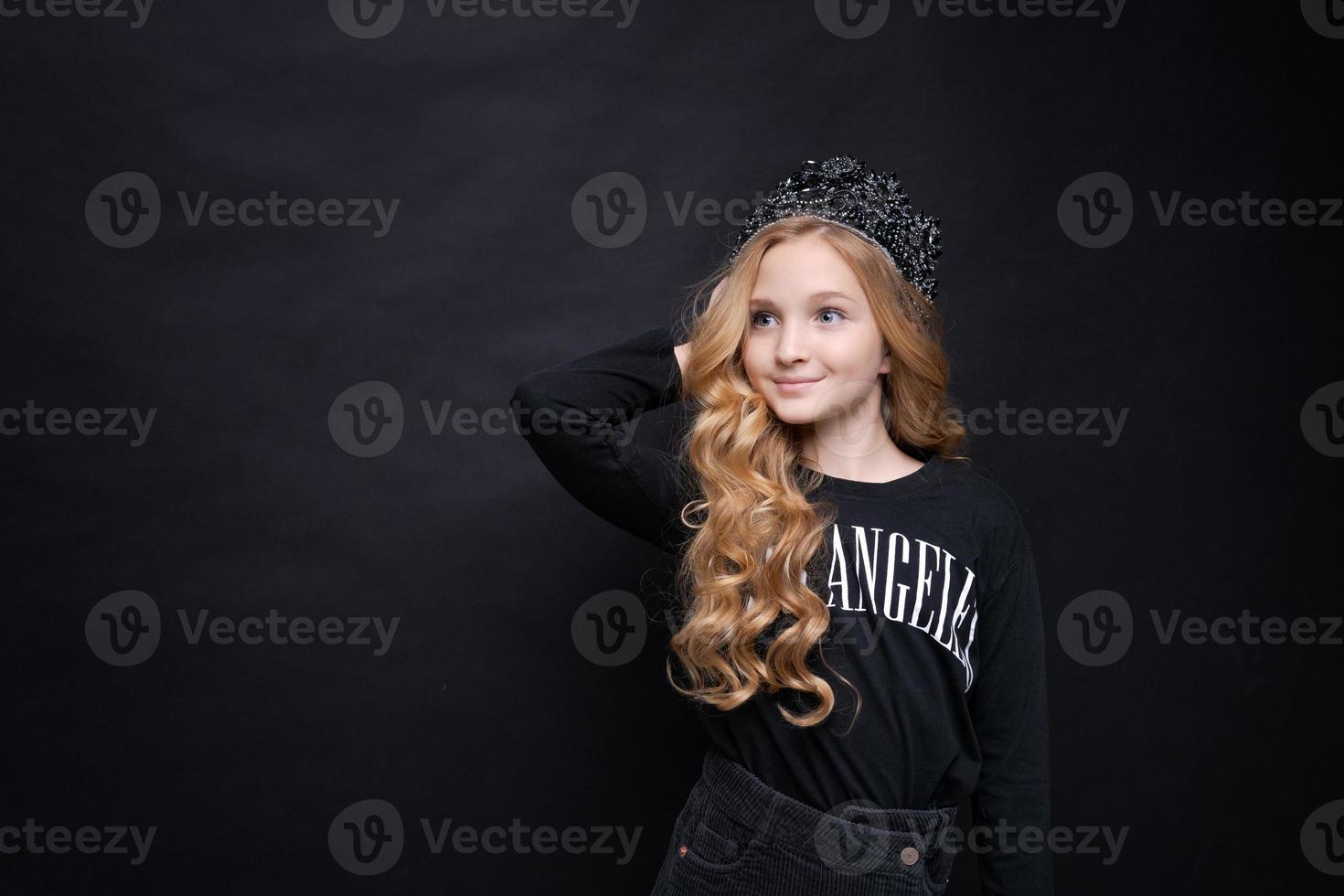 adorável menina sorridente feliz na coroa de princesa comemorando em preto foto