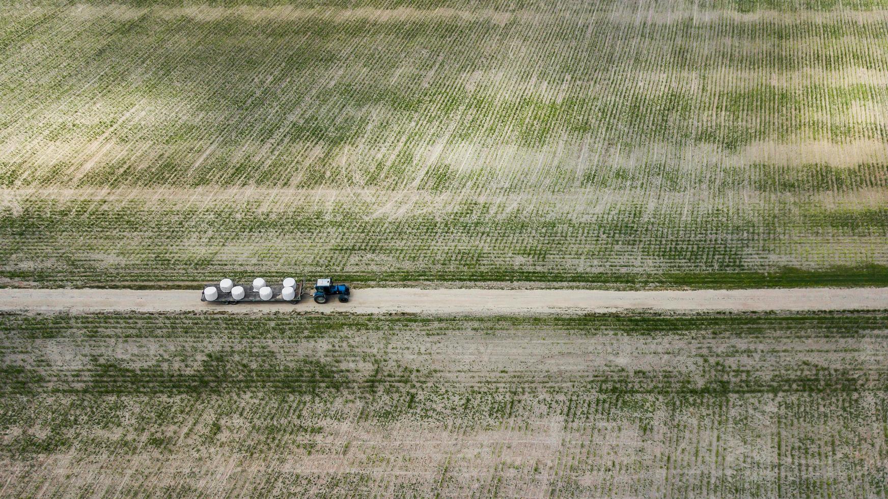 trator anda no campo e carrega fardos de feno vista aérea foto