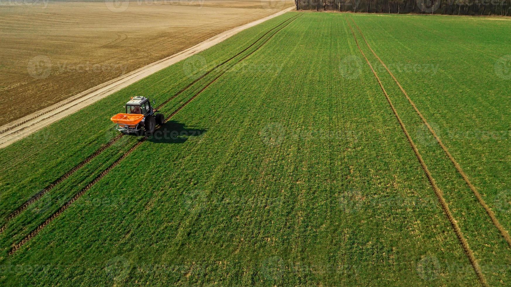 trator faz fertilizante no campo. levantamento aéreo foto