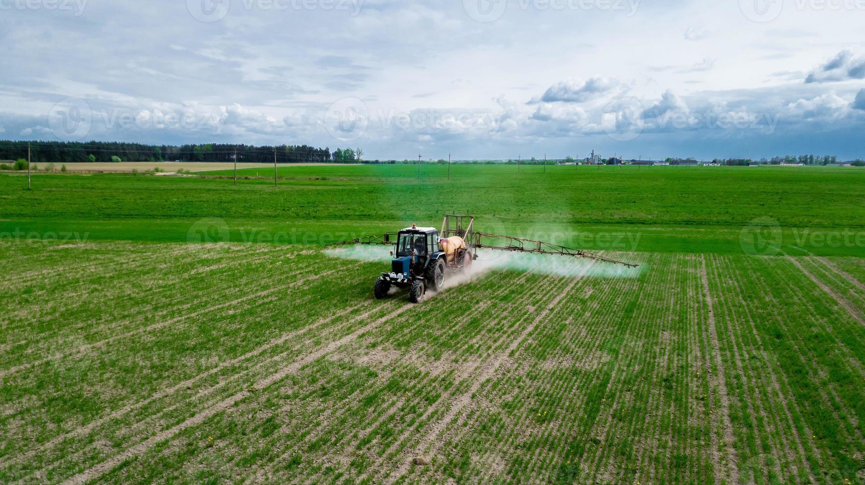 vista aérea, trator pulverizando pesticidas em campos de soja foto