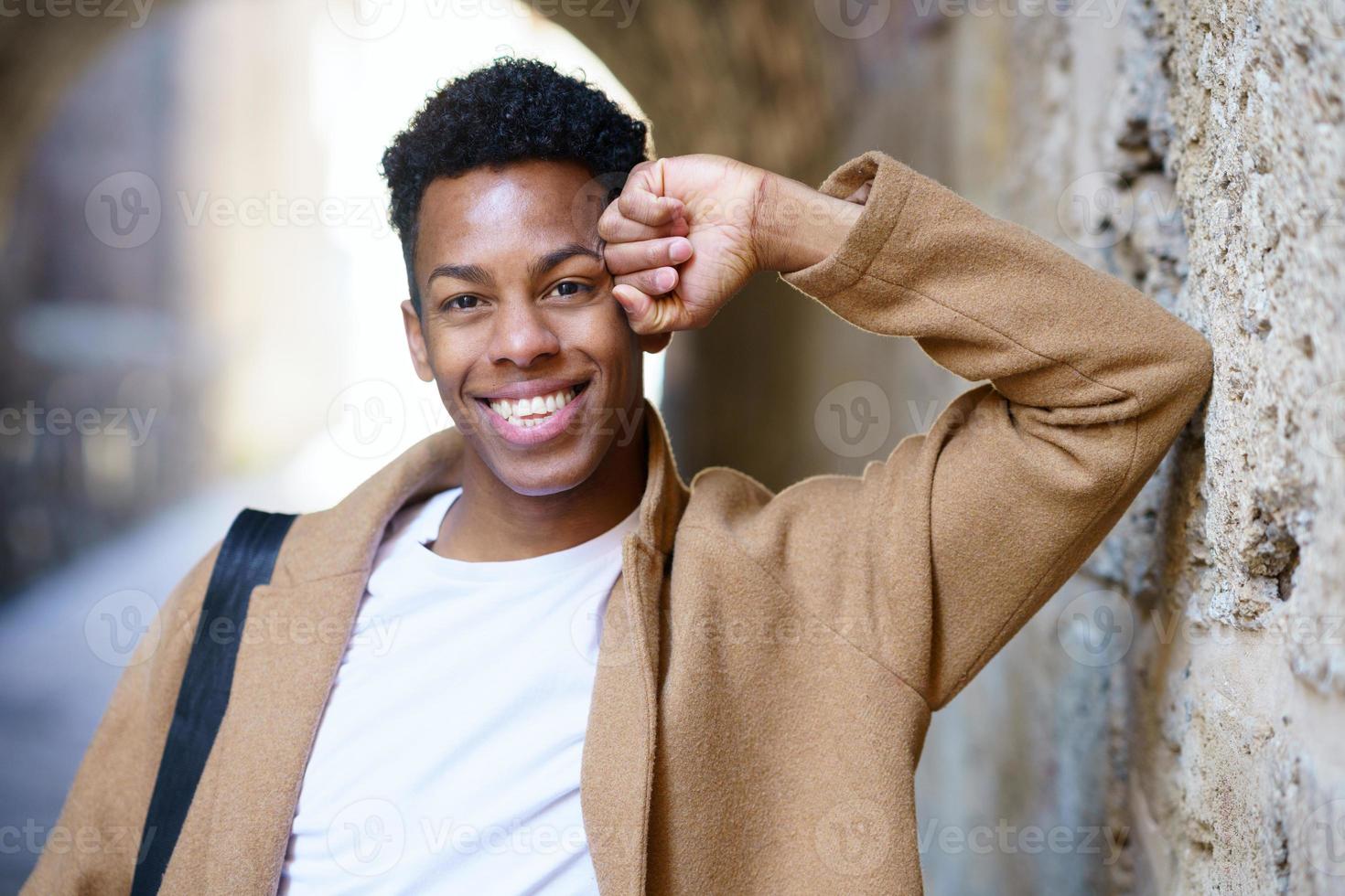 homem negro feliz sorrindo para a câmera ao ar livre. foto