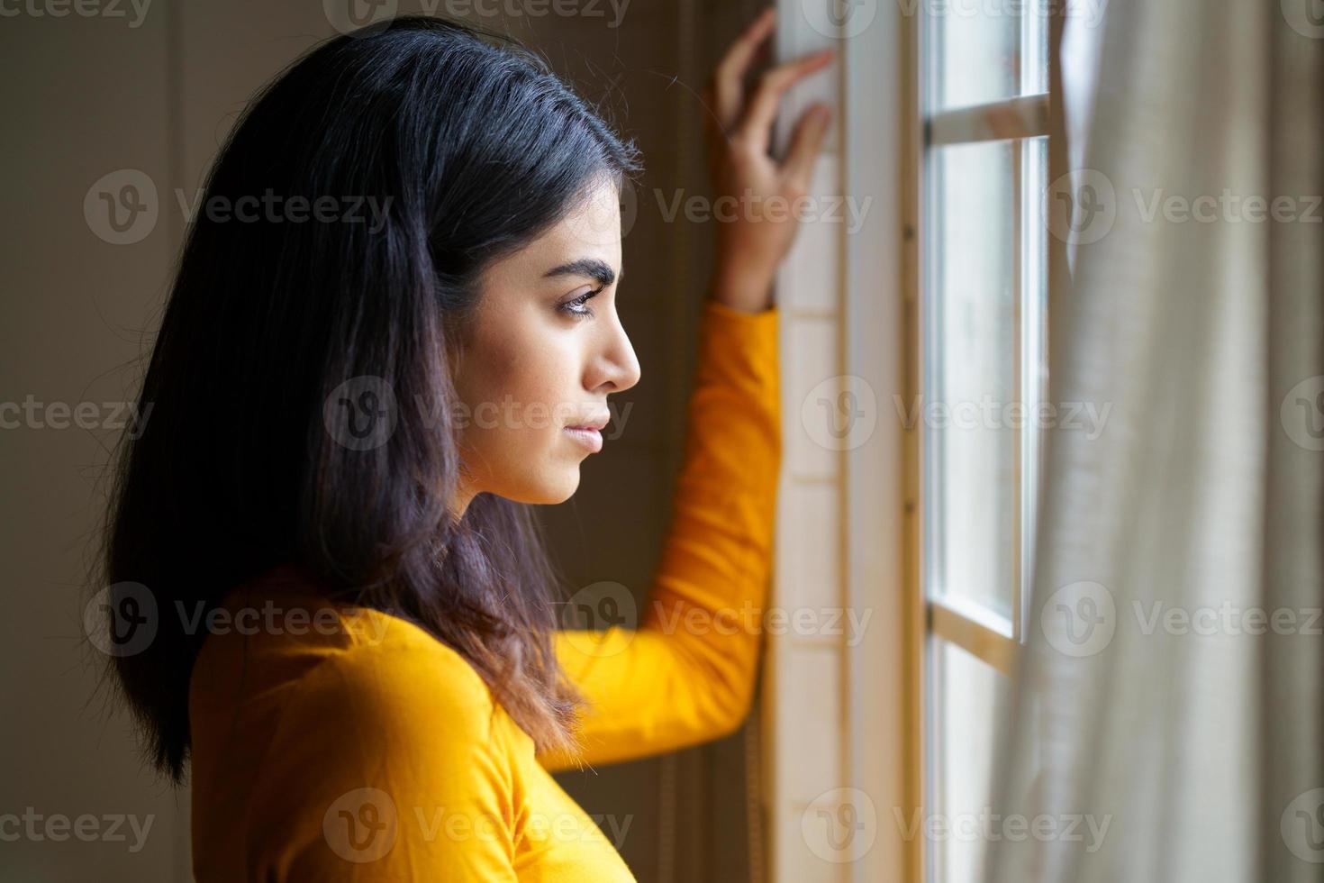 mulher persa olhando pela janela foto