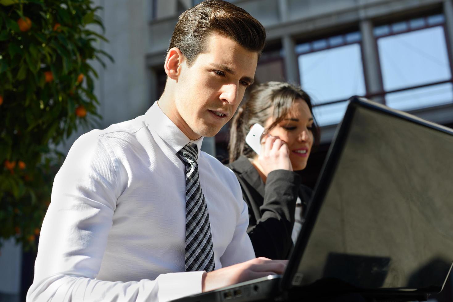 jovem empresário digitando em um laptop em meio urbano foto