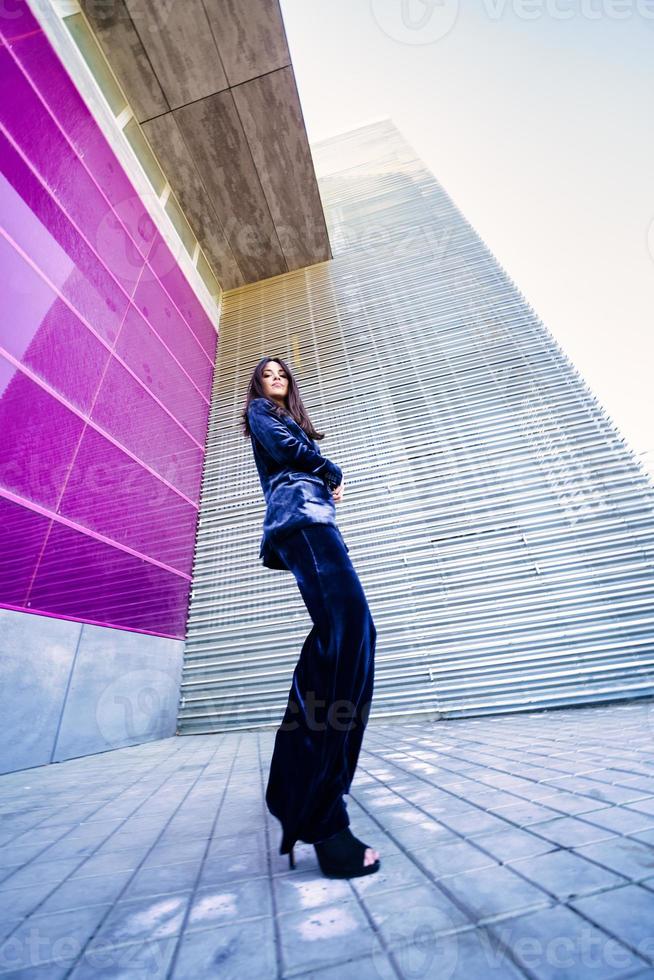 foto grande angular de uma mulher vestindo terno azul posando perto de um edifício moderno.