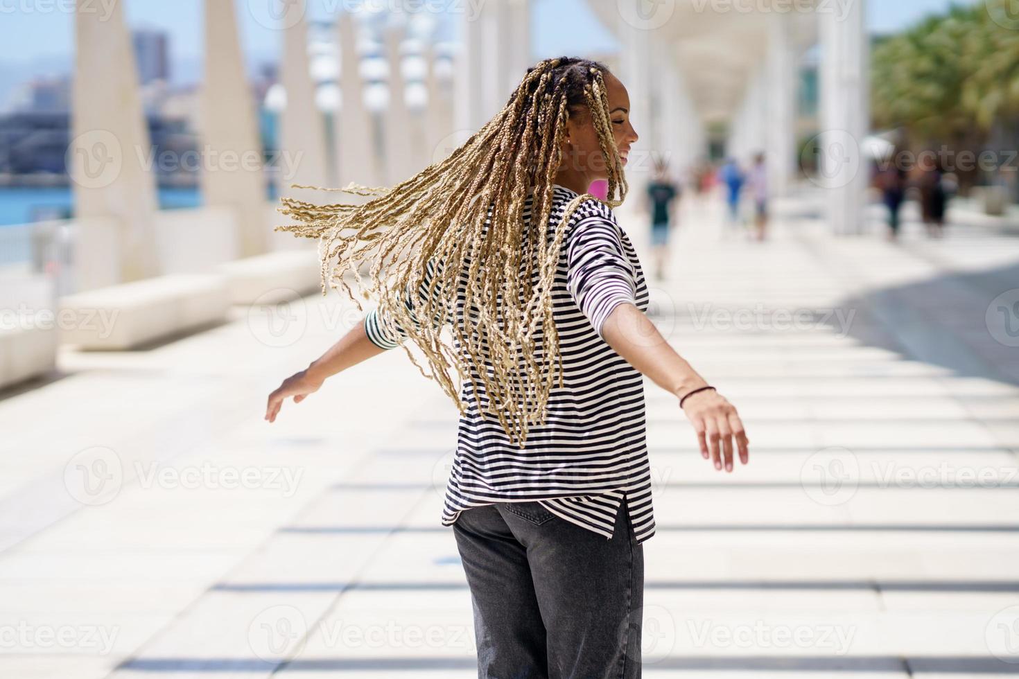 jovem negra movendo suas tranças coloridas ao vento. penteado africano típico. foto