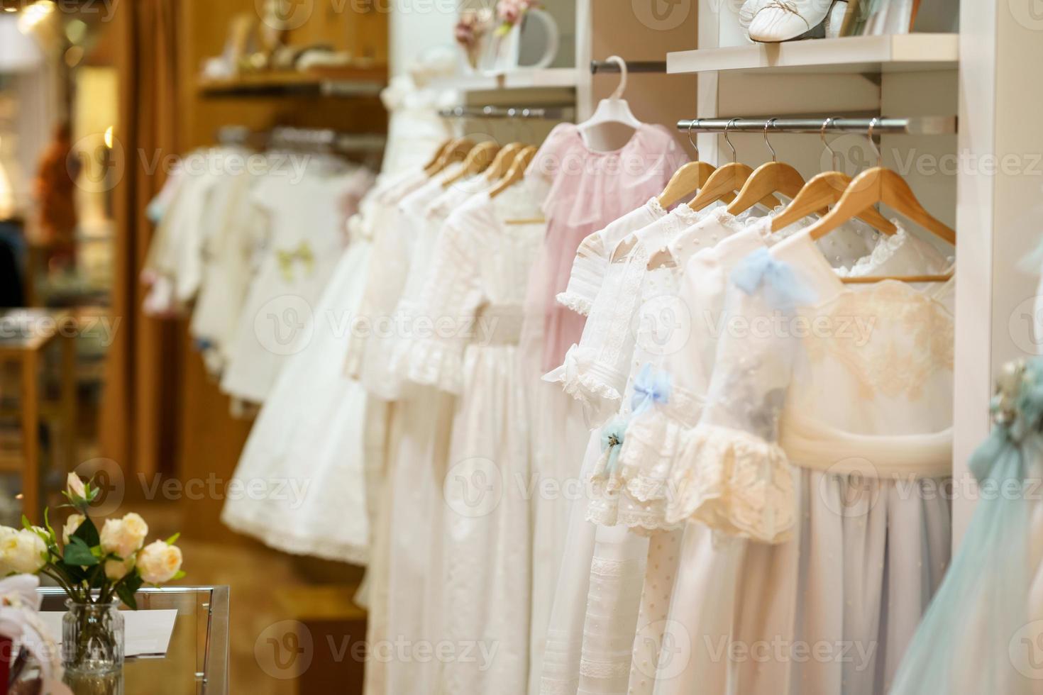 expositor com vestidos de primeira comunhão para meninas em uma loja de roupas infantis de luxo. foto