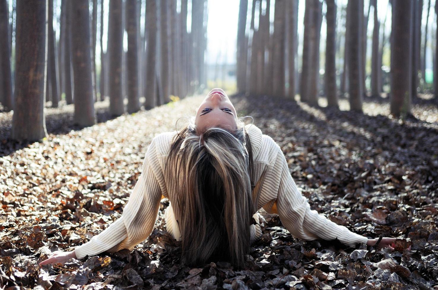 linda loira deitada em folhas em uma floresta de álamos foto