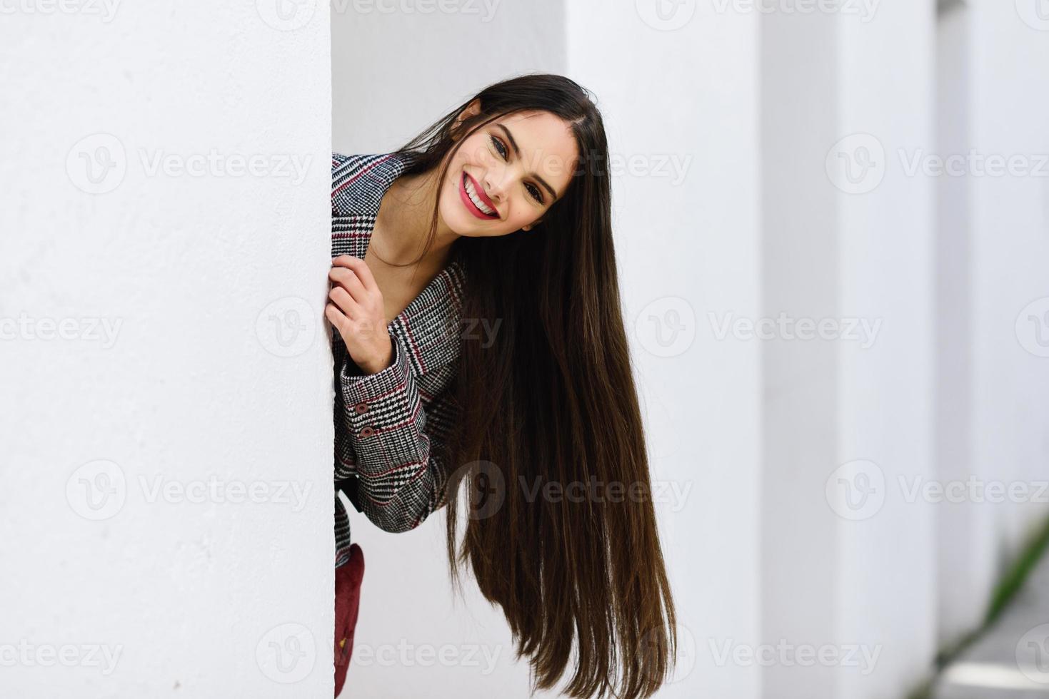 linda garota com cabelo muito comprido, vestindo casaco de inverno e boné ao ar livre. foto